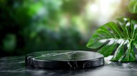 Black marble podium display stand with tropical monstera leaves in blurred natural garden background for product presentation and branding.