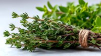 Fresh thyme and basil herbs tied with twine on white background, aromatic cooking ingredients for culinary use in Mediterranean cuisine.
