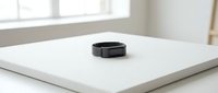 Smartwatch with black band and square face displayed on white tablet against bright window background, suitable for tech product marketing and wearable device promotions.