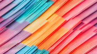 Vibrant diagonal stripes in pastel and neon colors create dynamic abstract pattern with layered paper sheets in pink, orange, blue and purple tones for modern design background.