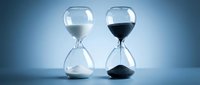 Two elegant hourglasses with white and black sand on blue gradient background symbolizing time passage, duality, balance and temporal concepts for business presentations.