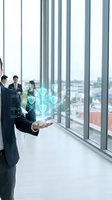 Business professionals in modern office displaying holographic security shield technology with cityscape view through floor-to-ceiling windows for corporate innovation and data protection concepts.