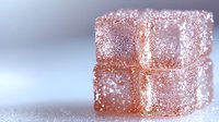 Pink sugar coated Turkish delight cubes stacked on white surface with soft focus background, sweet traditional Middle Eastern confectionery dessert.