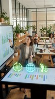 Diverse business team in modern office discussing ESG sustainability metrics with green technology icons and environmental data charts during corporate presentation.