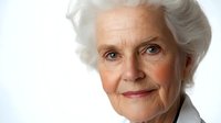 Senior Caucasian woman with white hair and gentle smile against white background, professional portrait showing confidence and wisdom in healthcare or business setting.