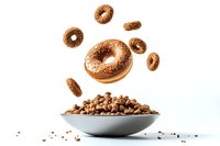 Flying chocolate glazed donuts and chocolate chips in gray bowl on white background, levitation food photography concept for menu and advertising.