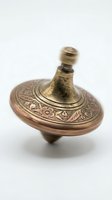 Antique brass spinning top with ornate floral engravings and decorative finial, isolated on white background for vintage toy and collectible product photography.