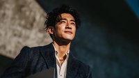 Young Asian businessman in elegant suit looking up with confidence and determination in dramatic lighting for corporate success concepts.