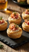 Gourmet puff pastry appetizers with prosciutto, cream cheese and rosemary garnish on slate board. Elegant party food for entertaining and special occasions.