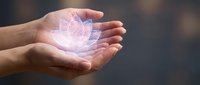 Caucasian hand holding glowing lotus flower hologram, representing spirituality, healing energy, and digital wellness technology for meditation and mindfulness applications.