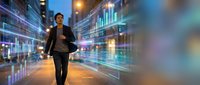 Young Asian businessman walking through futuristic digital city street with glowing data visualization and holographic financial charts at night.