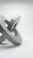 Abstract concrete sculpture with interlocking circular rings on white background for modern interior design and architectural concepts.
