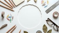 Office supplies arranged in circle frame with pencils ruler glasses and paper clips on white background for creative workspace design projects.