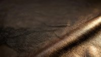 Brown leather texture with natural grain pattern and warm sunlight creating dramatic shadows and highlights for luxury material backgrounds.