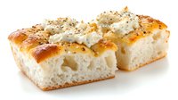 Freshly baked focaccia bread slices topped with creamy cheese and herbs on white background, showcasing soft interior texture and golden crust.