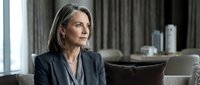 Professional mature Caucasian businesswoman in gray suit sitting thoughtfully in modern office interior with natural lighting and contemporary furniture.