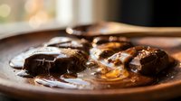 Rich chocolate brownies with glossy caramel sauce on rustic plate, warm kitchen lighting creates cozy dessert atmosphere for food photography and culinary content.