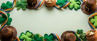 Overhead view of leprechaun hats and shamrock decorations arranged on pale green background, ideal for St. Patrick's Day celebrations and holiday marketing materials.