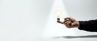 Business professional hand holding glowing light bulb representing innovation, creativity, and bright ideas for corporate success and entrepreneurship.