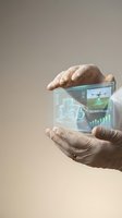 Hands holding futuristic holographic display showing smart farming technology with tractor drone and data analytics for precision agriculture innovation.