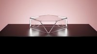 Transparent geometric glass bowl with angular faceted design on dark surface against soft pink background for modern home decor.