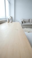 Minimalist wooden table in bright loft space with gray sofa, large window, and neutral decor. Scandinavian interior design for home, office, and lifestyle projects.