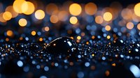 Dark water drop on glittering surface with golden bokeh lights in background creating magical atmosphere. Macro photography shows delicate details and reflections.