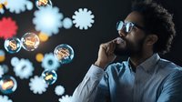 Young African American businessman in sunglasses contemplating while surrounded by floating soap bubbles and abstract light shapes, creating dreamy atmosphere for business vision concepts.