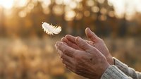 Close-up of weathered hands releasing a white feather into golden sunlight, symbolizing freedom, letting go, and spiritual release in nature.