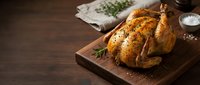 Golden roasted whole chicken with herbs on wooden cutting board, rustic kitchen setting with natural lighting for culinary and food photography.