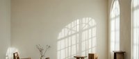 Minimalist dining room interior with natural sunlight casting window shadows on cream wall. Wooden furniture and dried branches create warm, serene atmosphere.