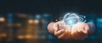 Hands holding glowing digital globe with orbital rings against blurred city lights, representing global connectivity, technology innovation, and worldwide business networks.