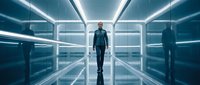 Middle-aged male professional in business casual attire walking through futuristic corridor with neon blue lighting and glass panels, suitable for corporate, technology, and innovation concepts.