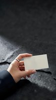 Hand holding a blank white business card mockup against dark textured background, ready for branding and corporate identity design.