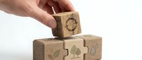 Hand placing wooden cube with recycling symbol on stack of eco-friendly blocks featuring sustainability icons for environmental awareness campaigns.