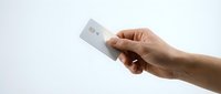 Hand holding blank white credit card or business card mockup against clean background for financial services and banking applications.