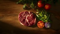 Raw ribeye steak with fresh tomatoes, herbs and red onion on rustic wooden background in dramatic lighting, food photography for restaurant menus.