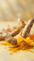 Fresh turmeric roots with golden powder spice on warm wooden surface for cooking, health supplements, natural medicine and culinary ingredients.