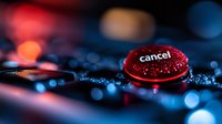 Red cancel button on dark keyboard with dramatic lighting and bokeh effect, macro photography showing technology detail and decision concept.
