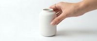 Hand holding a small white ceramic vase on a white background, minimalist home decor concept for interior design and lifestyle.