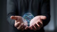 Professional businessman in dark suit holding glowing holographic brain with neural networks between cupped hands representing artificial intelligence and innovation.