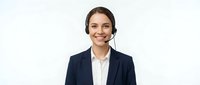 Professional young Caucasian businesswoman wearing headset smiling at camera in business suit against white background for customer service concepts.