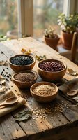 Wooden bowls filled with black beans, kidney beans, lentils and oats arranged on rustic table by window with potted plants, ideal for food and nutrition content.