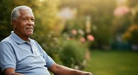 Senior African American man relaxing outdoors in garden setting, wearing light blue shirt, enjoying peaceful nature environment with blurred green foliage background.