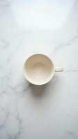 Empty white ceramic mug on marble surface, overhead view. Isolated on white background, ready for design use on merchandise and marketing materials.
