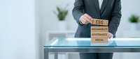 Professional businessman in suit stacking wooden blocks with ESG sustainability governance social text in modern office environment for corporate responsibility.
