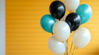 Festive bunch of black, white and turquoise latex balloons floating against vibrant yellow wall background, creating modern party atmosphere. Party decoration concept.