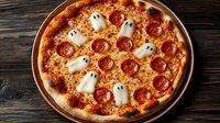 Halloween themed pepperoni pizza with ghost shaped mozzarella decorations on dark wooden background. Creative seasonal party food concept.