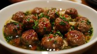 Juicy homemade meatballs in savory herb sauce garnished with fresh parsley. Tender beef spheres glazed with rich gravy create appetizing main course for dinner menu.
