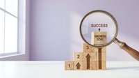 Wooden blocks forming ascending steps with magnifying glass highlighting success and growth goal concepts for business achievement and strategic planning.